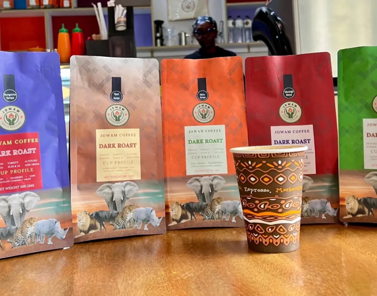 Bags of Jowam coffee lined up at the café bar with a takeaway cup