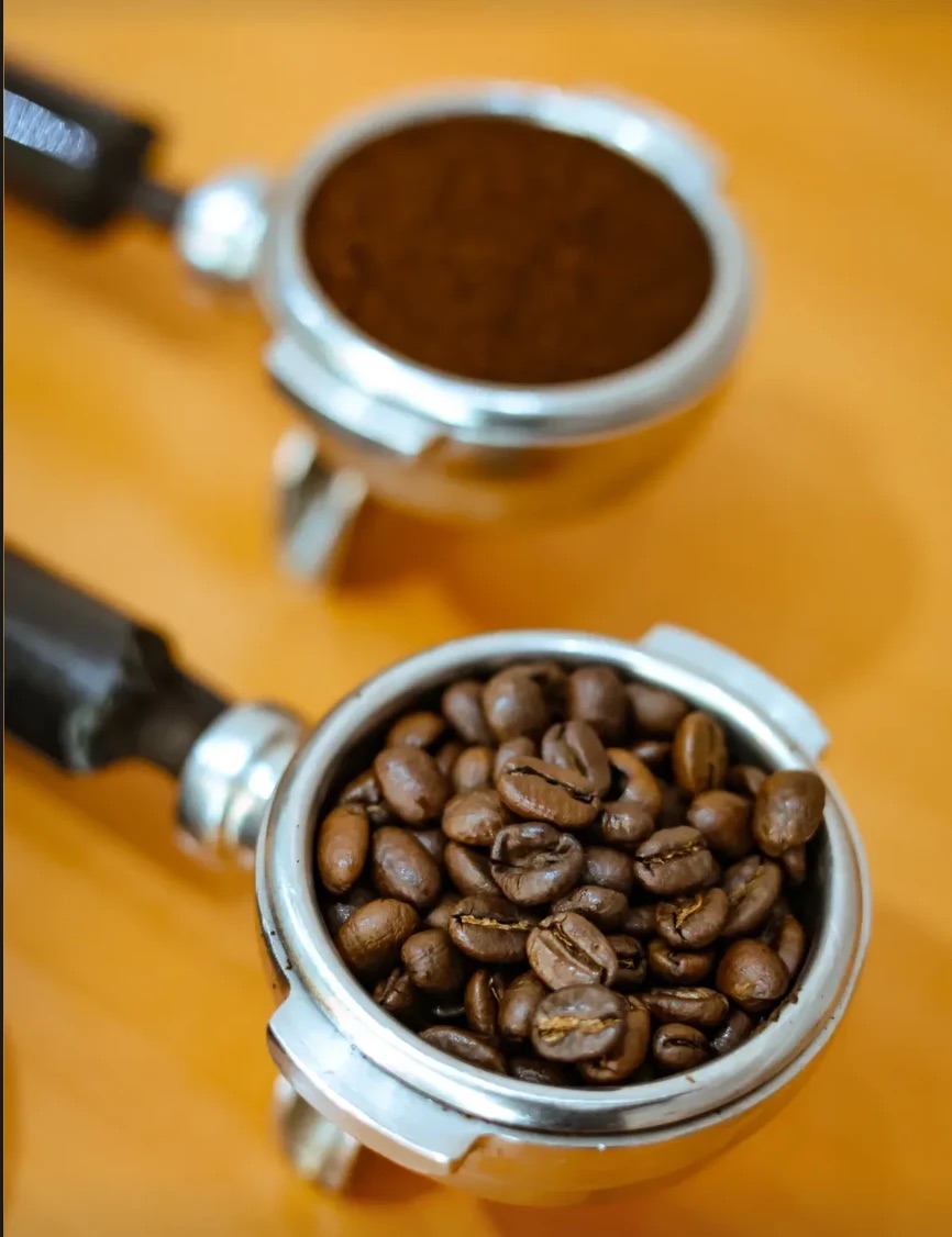 Two portafilters, one with whole beans and one with freshly ground coffee